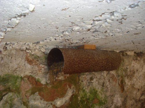 Vieux tuyau accroché au plafond d'un garage avec une petite inclinaison.